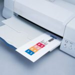 The Smead ColorBar ClickStrip, 250 Pack, Inkjet Printer (02781) hums efficiently, printing colorful numbered labels ranging from 1 to 8 in pink to blue on a light gray surface.