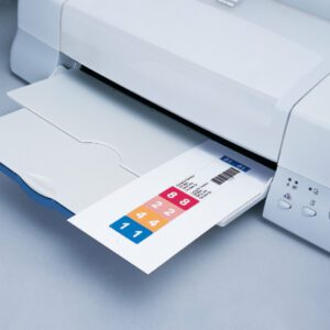 The Smead ColorBar ClickStrip, 250 Pack, Inkjet Printer (02781) hums efficiently, printing colorful numbered labels ranging from 1 to 8 in pink to blue on a light gray surface.