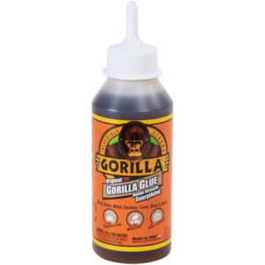 The 8 oz. Gorilla Glue® bottle with an orange label features the iconic Gorilla logo. It highlights its versatility on wood, stone, metal, ceramic, foam, and glass and comes with a white nozzle cap for precise application.