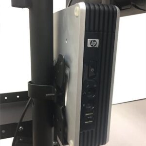 A compact HP desktop computer is mounted vertically on a stand, positioned behind a monitor. The front panel shows ports, a power button, and the HP logo. The stand is attached to a base on a flat surface.