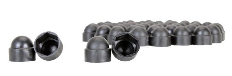 Close-up of Vestil Black Plastic Bolt Caps 1/2 In: multiple caps with rounded tops and hexagonal inner shapes. The foreground group shows the open side, while the background group is blurred.