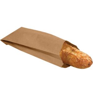 A crusty baguette peeks from a 3 3/4 x 2 1/4 x 11 1/2 Kraft Grocery Bag (2000/Bundle), resting on a white background.