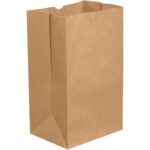 A large, upright 12 x 7 x 17 Kraft Grocery Bag with a rectangular base and open top stands empty against a white background. The bag is folded neatly, displaying typical creases, reminiscent of those found in bundles of 500.