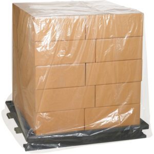 A stack of brown cardboard boxes wrapped in MH-USA 46 x 36 x 65 - 2 Mil clear pallet covers sits on a black pallet, highlighting their durability.