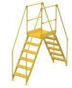 The Vestil Cross-Over Ladder 6 Step 58 H 26 W is a yellow metal industrial ladder featuring dual steps to a small platform with safety handrails, perfect for accessing high areas in warehouses or factories.