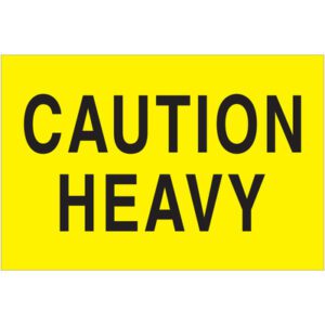 A bright fluorescent yellow warning sign with bold black CAUTION HEAVY text mirrors the design of MH-USAs 2 x 3 Caution - Heavy (Fluorescent Yellow) Labels (500/Roll).