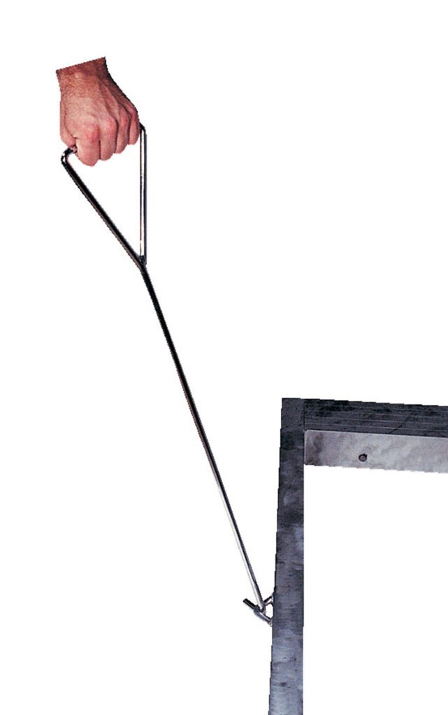 A hand grips a metal hook tool similar to the Vestil Option-Loops/Handles Alum Pallet Dollys sturdy handle, using its triangular grip and long shaft for leverage to lift a manhole lid against a plain white background.