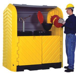 A worker, wearing safety gear, pours liquid from a red container into a funnel on a black drum inside a Vestil Hard Top Drum Storage-2 Drum With Drain while the yellow chemical storage cabinet stands open, displaying its organized contents.