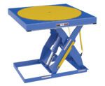 The Vestil Built-In Manual Scissor Table Carousel-Ehlt has a blue hydraulic lift, square base, and round yellow platform. Designed for industrial tasks, it includes safety measures for efficient lifting or rotating of objects.