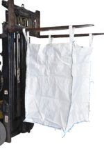 A large white bulk bag, resembling the Vestil Fabric Hopper 3.3K 50 Cu Ft, hangs from the forklift forks. With dimensions of 36 X 36 X 55 and reinforced lifting loops, it’s designed for heavy-duty transport. The forklift is partially visible on the left side.