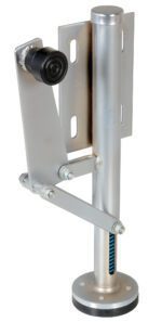 A metallic support leg with a circular base and vertical rod, featuring a side gear mechanism, similar to the Vestil Floor Lock Right Side Mount. It includes a top bracket with mounting holes and a horizontal bar ending in a black rubber stopper.
