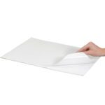 A hand raises the corner of a stack of MH-USA 15 x 15 - Freezer Paper Sheets (50Lbs/Bundle) against a pristine white background, showcasing their crisp and versatile design.