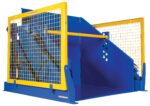 The Vestil Electric/Hydr Box Dumper 6K 36 In Dump H features a blue industrial design with yellow safety grates and railings. Its geometric structure and circular cutouts ensure durability, making it perfect for manufacturing or processing tasks.