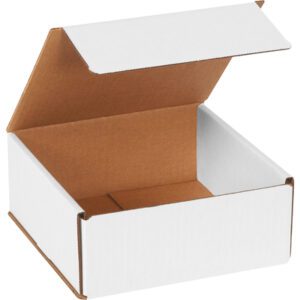 An open MH-USA 7 x 7 x 3 white corrugated mailer, with a hinged lid and brown interior, is slightly angled upwards to the right, revealing its depth and empty interior.