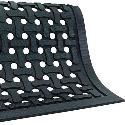 MAT218.jpg A black MH-USA 4 x 6 Slip Guard Drainage Mat features a woven pattern with circular cutouts and is displayed at an angle. Its textured surface enhances its geometric look, offering both style and practicality.