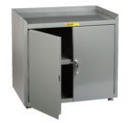 A gray metal cabinet, similar to the Little Giant Stationary Shop Cabinets w/Leg Levelers, has one door partially open, showing an inner shelf. It features a flat top and adjustable feet for elevation. A small label with text decorates the front.