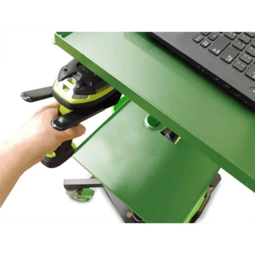 A person holds a green and black handheld scanner near a green metal cart with a laptop on top. The cart has multiple shelves, and the scene suggests a workspace or inventory setting.