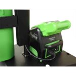 Close-up of a green and black Nucleus PowerDock Station with a connected battery. The device features labels and multiple connection ports, positioned on a black surface.