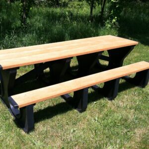 A Vestil Picnic Table with a cedar top and two benches, featuring the Poly Walk Thru 2896 BK Leg design, sits on the grass. Contrasting black supports amid trees suggest a sunny day—a perfect spot to enjoy nature.
