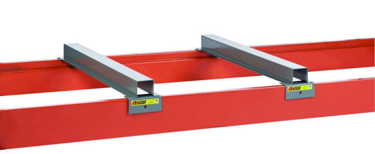 Two gray rectangular metal brackets attach to a red metal beam, resembling parts of the Little Giant Rack Deck Clearance Bar. Yellow caution labels enhance safety in this industrial assembly, with a white background highlighting its structured precision and functionality.