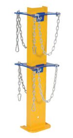 The Vestil Cylinder Storage Stand is a yellow vertical metal post with two blue horizontal plates. Each plate has two chains with hooks, and its flat base ensures stability for reliable cylinder storage.