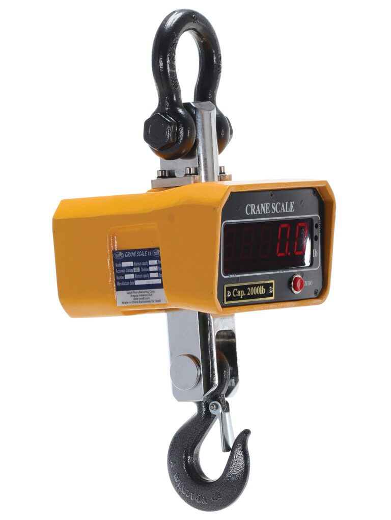 The Vestil Crane Scale with 2000 lb capacity, dimensions of 8 x 7.625 inches, shows 0.0 on its LED screen and features a hook and shackle. A side label details its specs.