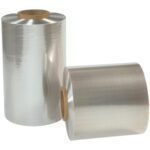 Two rolls of 24 x 75 Gauge x 500 Reynolon® 5044 PVC Shrink Film (1 Roll/Case) stand upright with shiny surfaces wound around cardboard cores, highlighting the clear plastic wraps premium quality.