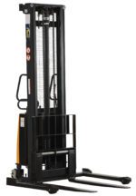 The Vestil Adjustable Stacker W/Powered Lift 150 In is a black stacker with two prongs, a powered lift, vertical mast with chains and gears, side hand controls, caution labels, and an industrial design.