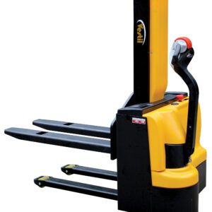 The yellow and black Vestil Stacker features two long forks and small wheels for easy pallet handling, control buttons on the handle, and a red emergency stop button for safe operation.