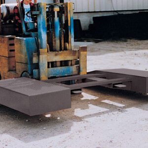 Operating a forklift with a custom attachment, featuring a sturdy metal frame and large flat panels, the operator utilizes the Vestil Wheel Riser Option - Pickup Loop on the dirt surface near the building for better stability during loading.