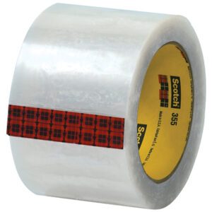 The 3 x 55 yds. Clear Scotch® Box Sealing Tape 355 (24/Case) has a red and black plaid strip encircling it with the Scotch 355 label, and text printed on the inner cardboard ring.