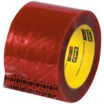 A partially unrolled roll of 3 x 110 yds. red Scotch tape with a yellow core, branded as 3M Security Message Box Sealing Tape 3779, sits by its packaging. The brand logo is visible on the inner side.