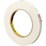 A roll of white 1/2 x 60 yds. Scotch® Filament Tape 897 sits at an angle, label partially visible. Its exposed strip hints at durability, promising reliable packaging in this convenient 12-pack.