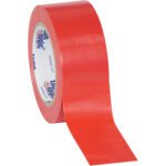 A partially unrolled roll of wide red adhesive tape reveals an inner label with text and logos. This Tape Logic® 2 x 36 yds. Red (3 Pack) is made from solid vinyl for improved safety and durability.