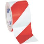 A partially unrolled roll of red and white diagonal striped tape sits on a plain white background. This 3 x 36 yds. Tape Logic® Striped Vinyl Safety Tape comes in a 3-pack, ideal for clearly marking hazardous areas.