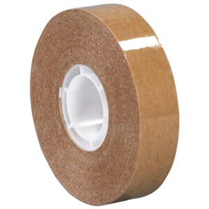 A 2-pack of Tape Logic® Heavy-Duty Adhesive Transfer Tape (1/2 x 18 yds.) stands upright against a plain background; the brown, glossy tape is partly unwound from its white plastic core, revealing the adhesive side.