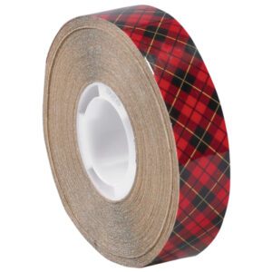 The 1/4 x 18 yds. 3M™ 926 Adhesive Transfer Tape features a red and black plaid design with thin yellow stripes, is partially unwound to show its adhesive layer on a white plastic core, and comes in cases of 72 rolls for crafting needs.