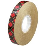 The 3/4 x 36 yds. (6 Pack) 3M™ 924 Adhesive Transfer Tape features tightly wound transparent tape on a brown spool with a white core and a striking red and black plaid outer wrap featuring yellow stripes.