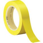 A roll of 1 x 36 yds. Yellow 3M Vinyl Tape 471 lies partially unwound, with 471 and Made in USA on the hub, and is displayed at an angle against a white background, highlighting its vivid hue and smooth texture.