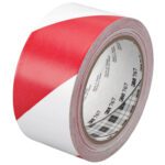 A roll of 2 x 36 yds. Red/White 3M Safety Stripe Vinyl Tape 767, featuring diagonal stripes and visible branding on the inner core, is partially unrolled to display its pattern, ensuring optimal visibility for safety uses.
