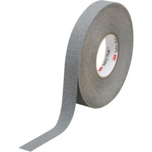 A roll of 1 x 60 Gray 3M™ Safety-Walk™ Tape - 370 stands upright with part of the textured tape unrolled, showing the brand on the inner core. This essential anti-slip tape offers safety and durability and is available in a case of four rolls.
