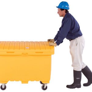 A person in protective gear, including a blue helmet, dark shirt, white pants, gloves, and black boots pushes a large yellow Vestil Utility Box with rubber wheels.