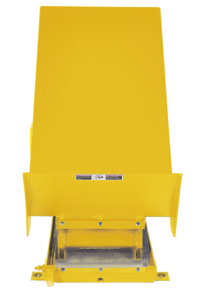 A yellow rectangular metal device similar to a Vestil Lift Table 2K 24X48 Yellow 208V 3 Phase, featuring a chute, warning labels, and a small base lever for material dispensing or processing.