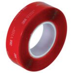 The glossy red 3M VHB tape with white text and visible white adhesive backing unfurls, set against a plain backdrop, highlighting its versatile appeal similar to the Clear 1 x 5 yds. 3M™ 4905 VHB™ Tape (1 Roll/Case).