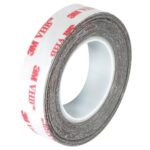 A partially unrolled roll of 1/2 x 5 yds. white 3M™ 4932 VHB™ Tape displays its thickness and side view with red 3M VHB text, standing upright against a pristine white background.