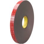 The 1 x 5 yds. Black 3M™ 4979F VHB™ Tape (1 Roll/Case) features a distinctive red outer layer with a yellow inner core, offering dependable adhesion for diverse uses with its thick and coiled design.