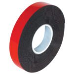 A 1/2 x 5 yds. roll of dark gray 3M™ 5952 VHB™ Tape, featuring red backing and coiled around a white core, partially unrolls to show its adhesive side for versatile use.