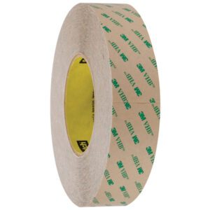 A roll of 1 x 5 yds. Clear 3M™ F9460PC VHB™ Tape is showcased upright, highlighting its circular form and adhesive interior with brown paper backing and green text, underscoring its quality as an essential tool.