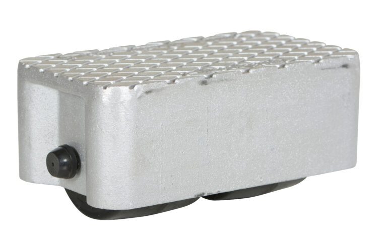 A silver metal foot pedal, similar to the durable Vestil Cast Aluminum Dolly 3000 Lb 8.5L X 4.75W, features a textured grip surface and a round black side knob. Its angled base with two visible black rollers ensures smooth maneuverability for up to 3000 lb loads.