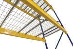 Low-angle view of Vestil Pallet Rack Wire Decking, 42 in x 46 in industrial shelving with yellow-bordered shelves and sturdy blue beams against a white background.